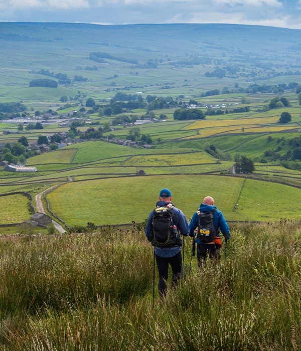 Two people walking through a field with a beautiful view